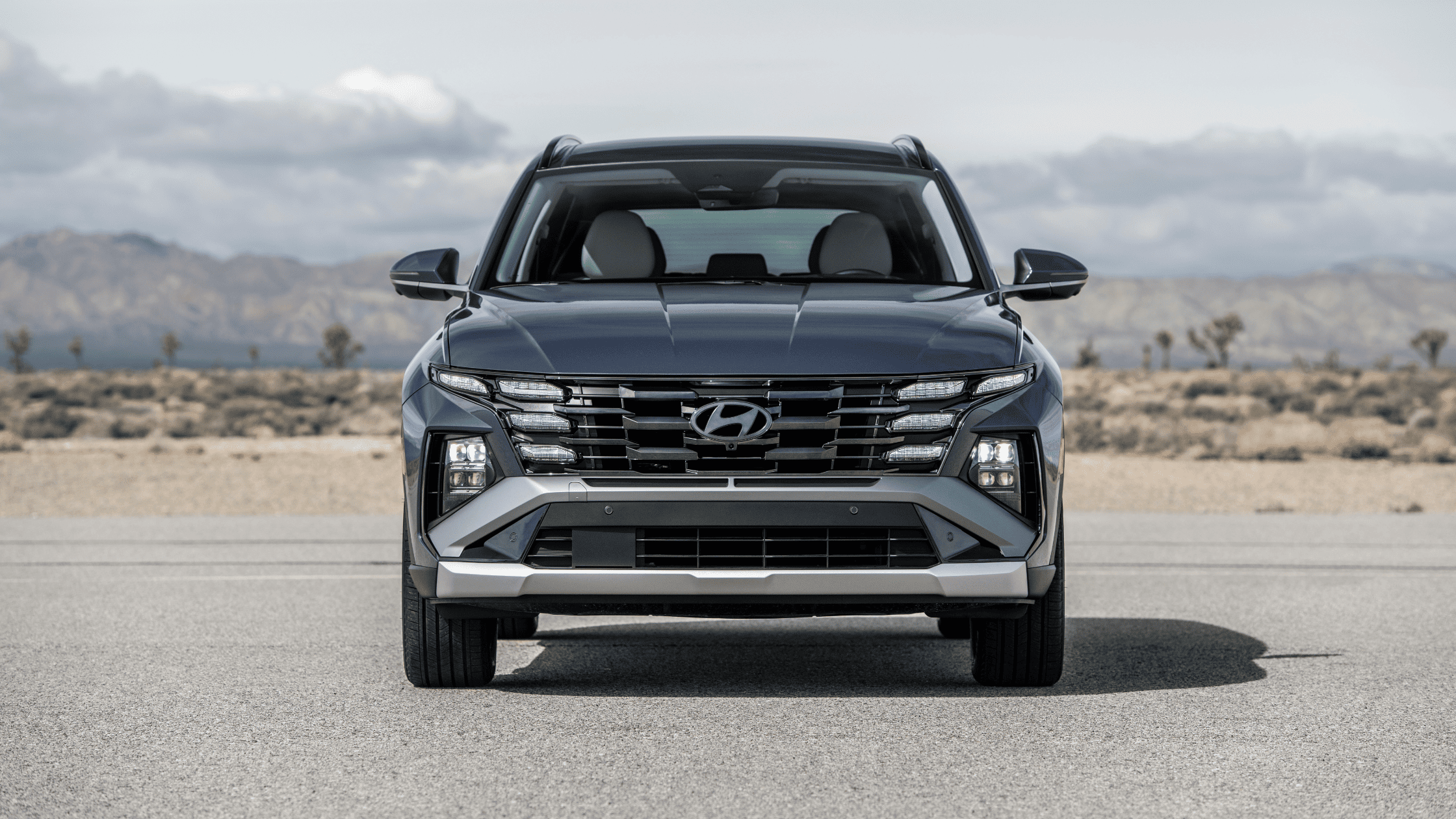 Front view of the 2025 Hyundai Tucson SUV parked with mountains in the background.