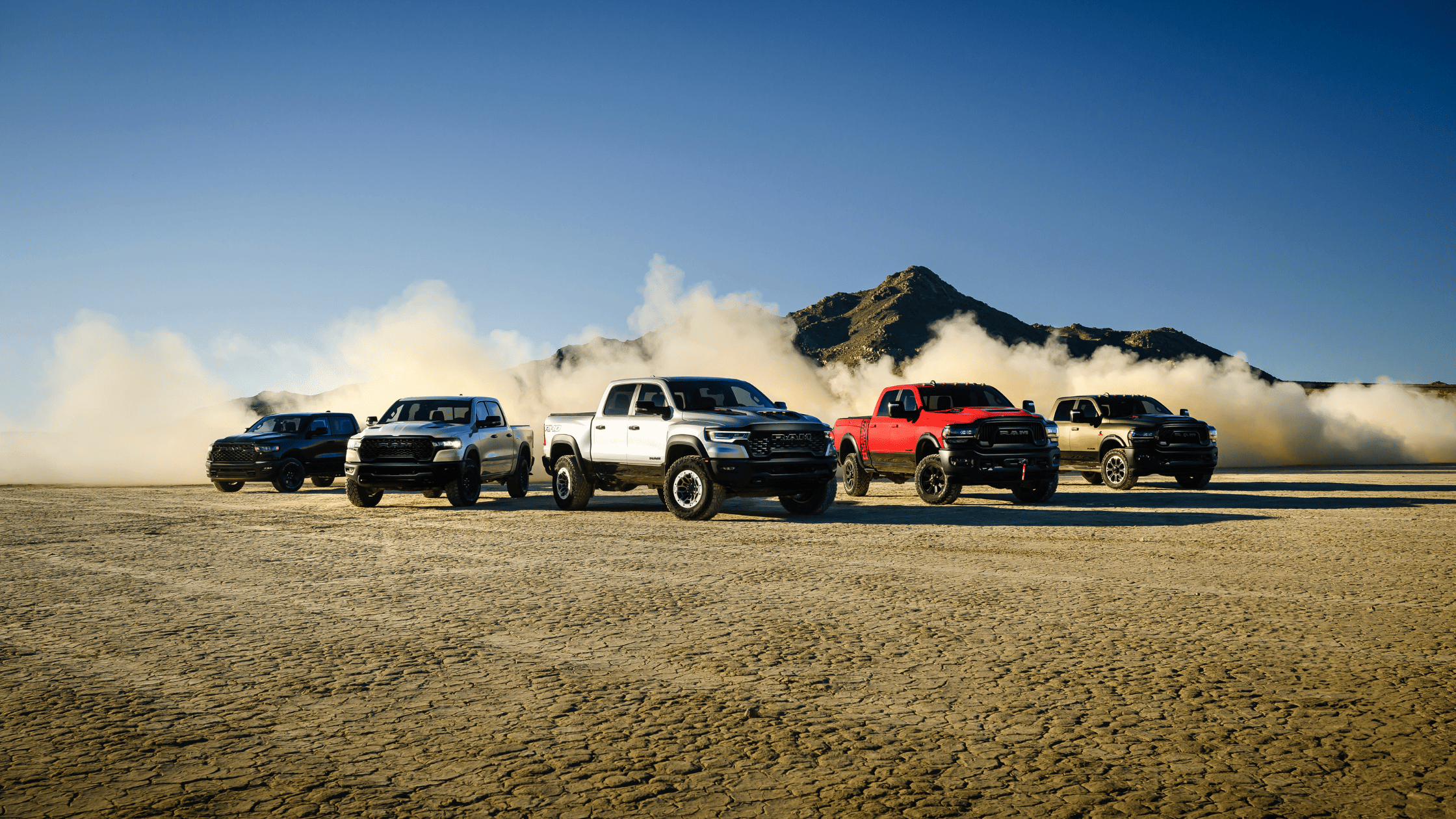 2025 Ram 1500 lineup kicking up dust on cracked desert terrain