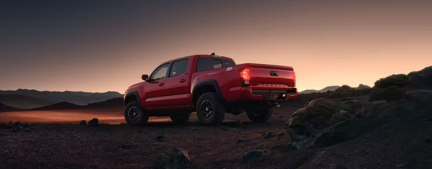 A red 2023 Toyota Tacoma SR5 SX is parked off-road after dusk.