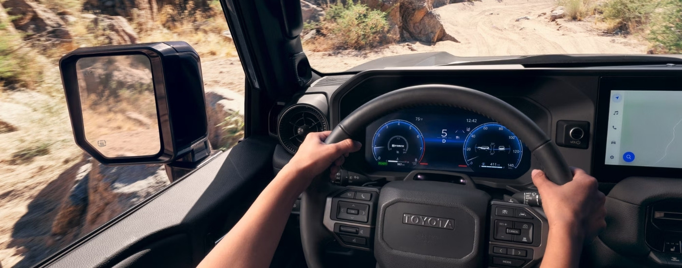 A person steering a 2025 Toyota Land Cruiser.