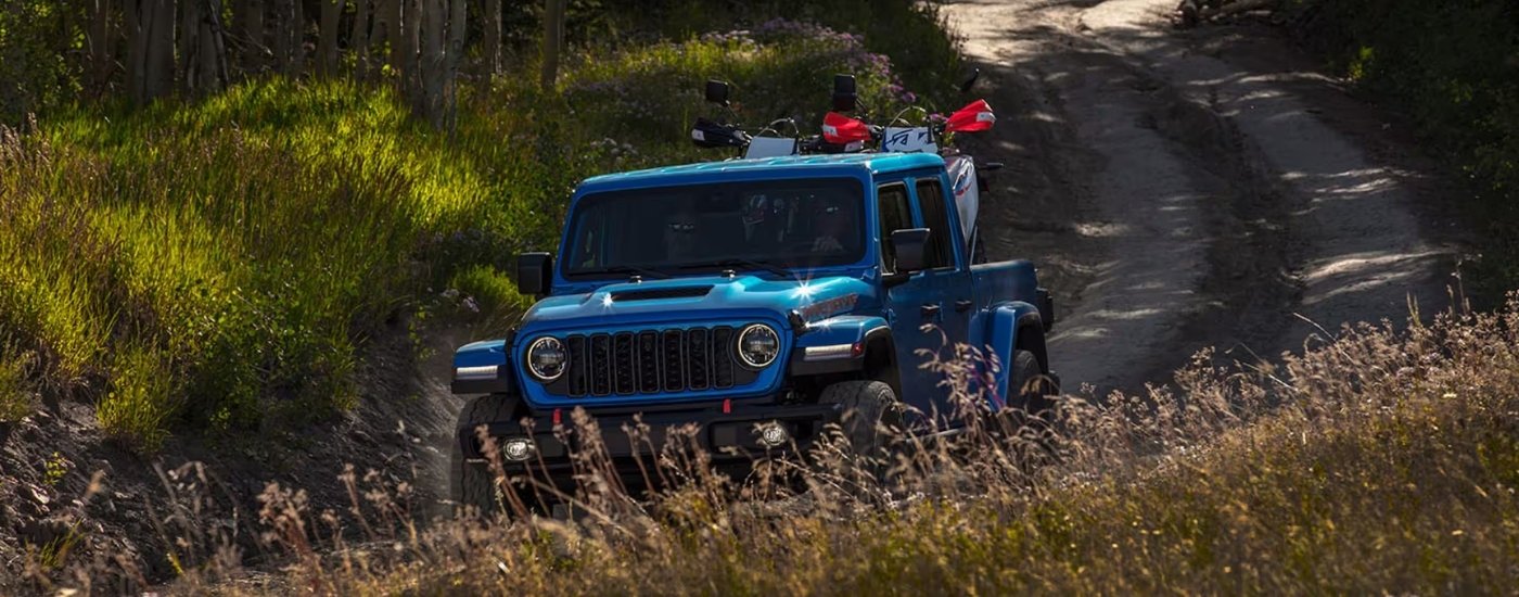 A blue 2023 Jeep Gladiator hauling dirt bikes.