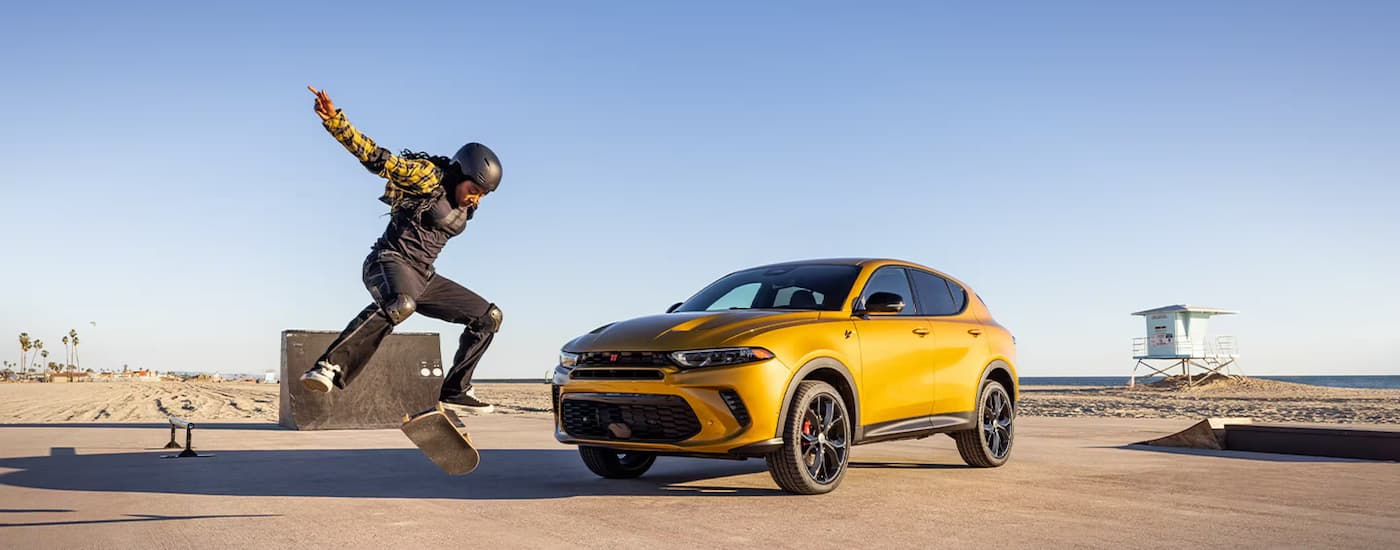 Person skateboarding next to a yellow 2025 Dodge Hornet.