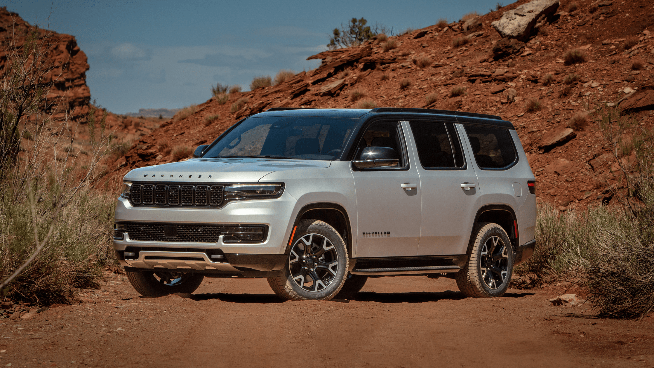Silver 2025 Jeep&reg; Wagoneer parked on a rugged dirt trail surrounded by red rock canyon terrain.