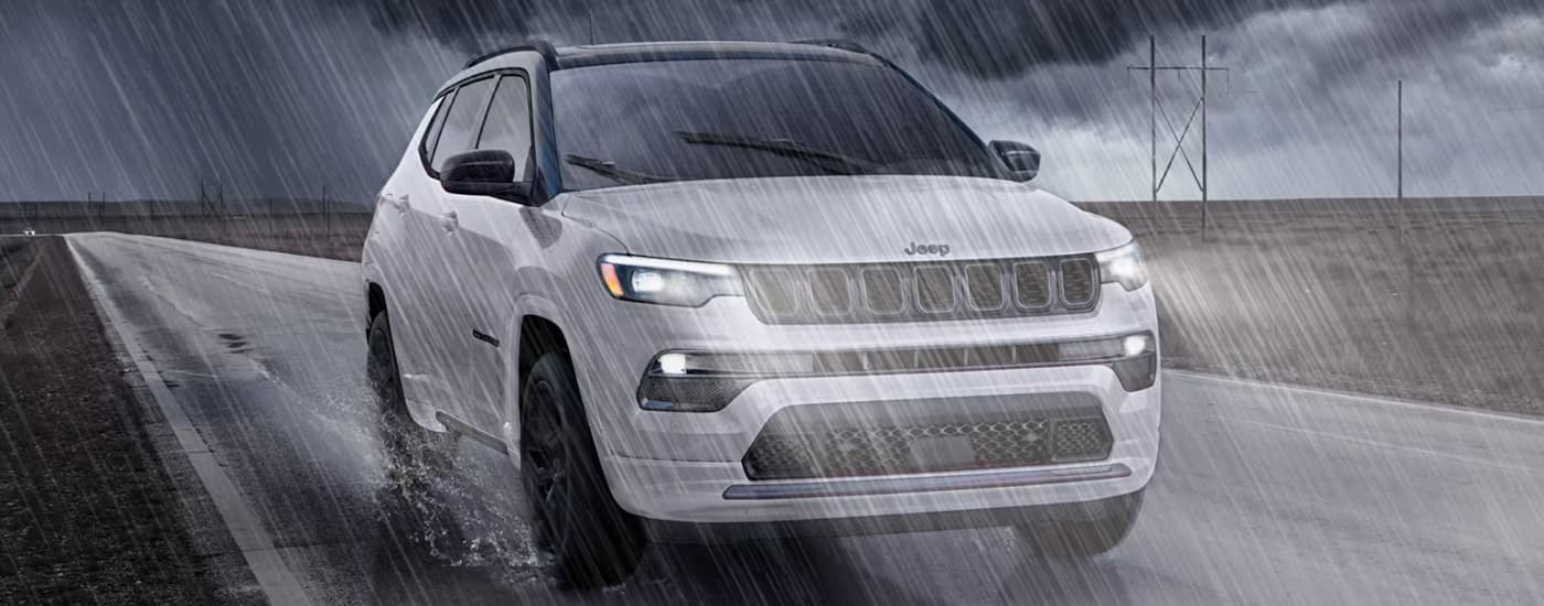 White 2025 Jeep Compass driving in the rain.