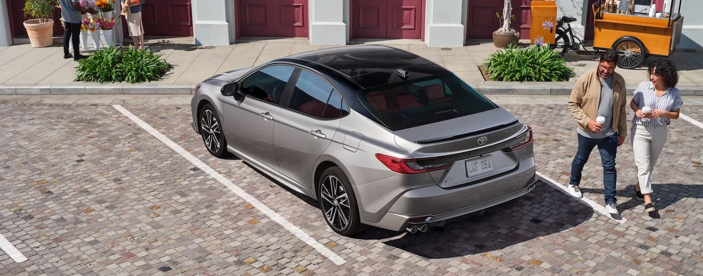 Couple walking by parked silver 2025 Toyota Camry.
