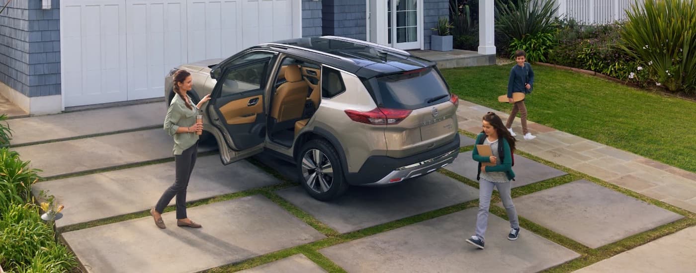 A tan 2023 Nissan Rogue from the rear at an angle.