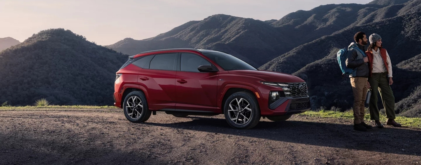 Hikers near a red 2025 Hyundai Tucson Hybrid.