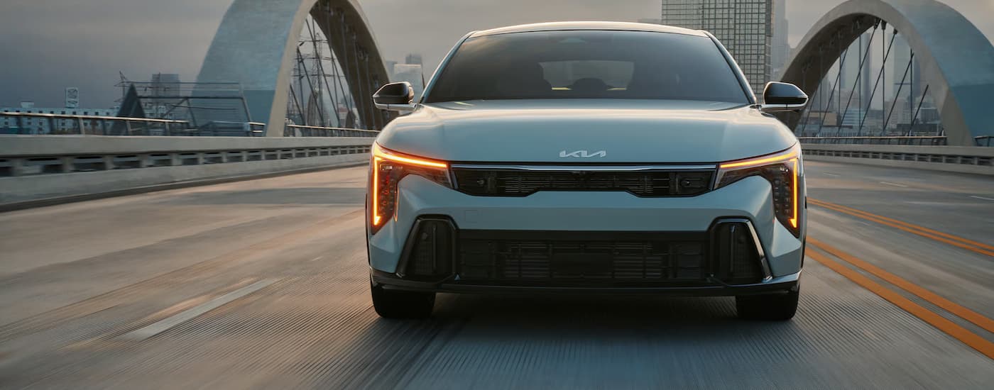 Grey 2025 Kia K4 driving on a bridge to a Kia dealer near Lincoln.