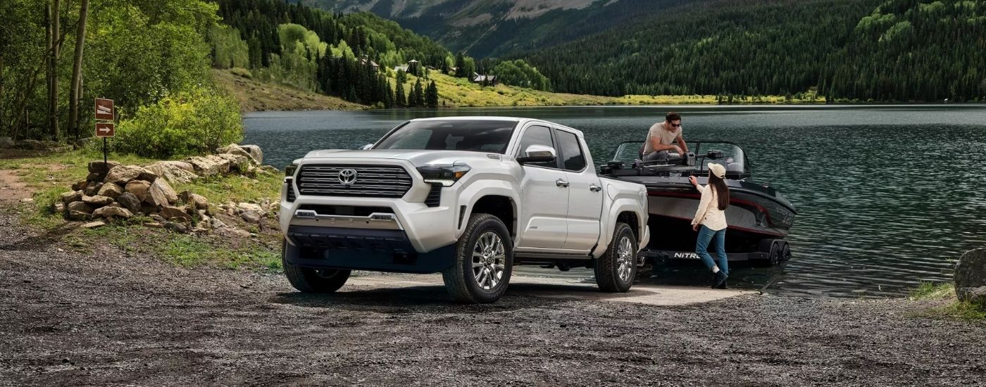 A white 2025 Toyota Tacoma from the front at an angle loading a boat.