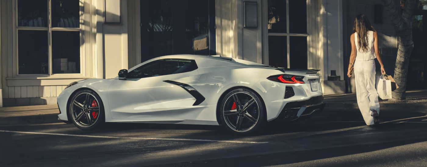 A white 2025 Chevy Corvette Stingray in front of a shop.