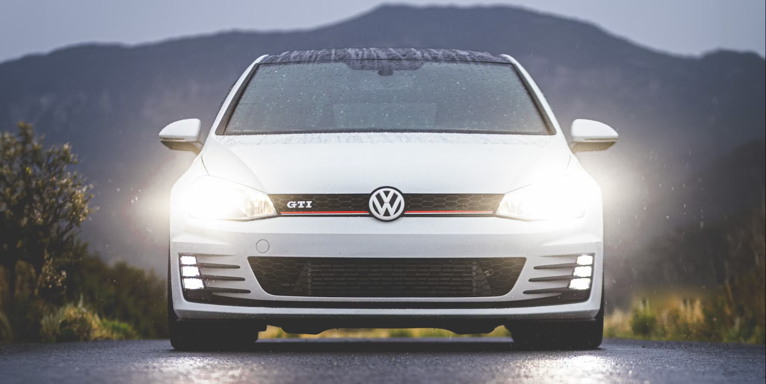 a front view of a white VW GTI with headlights turning on