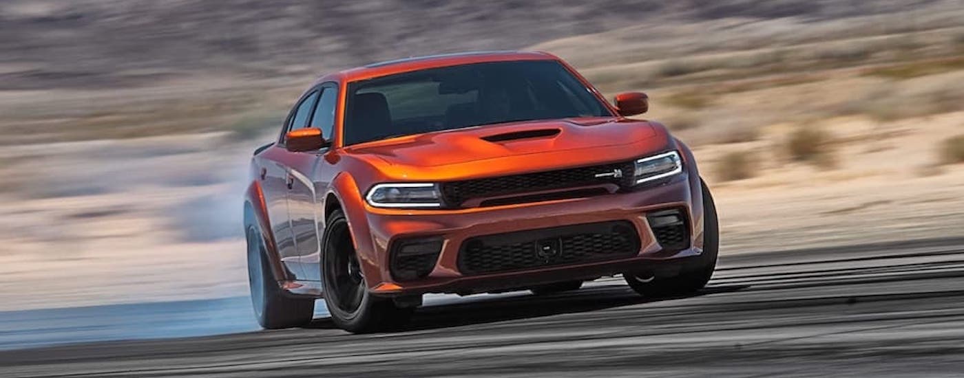 An orange 2023 Dodge Charger from the front after leaving a dealer with a used Dodge for sale.