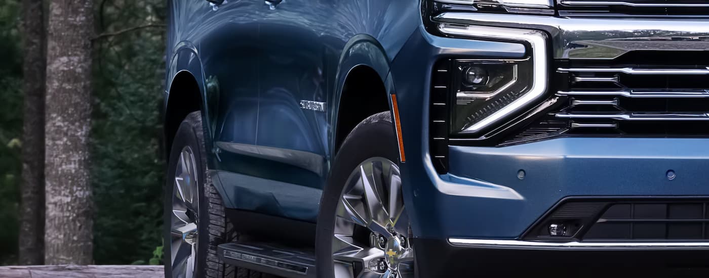 Headlight and side of a blue 2024 Chevy Suburban for sale near Magnolia.