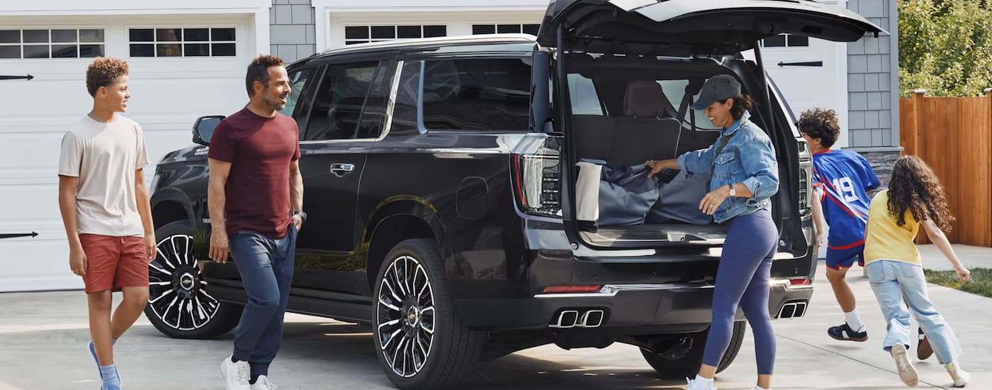 Family around a black 2025 Chevy Suburban in a driveway.