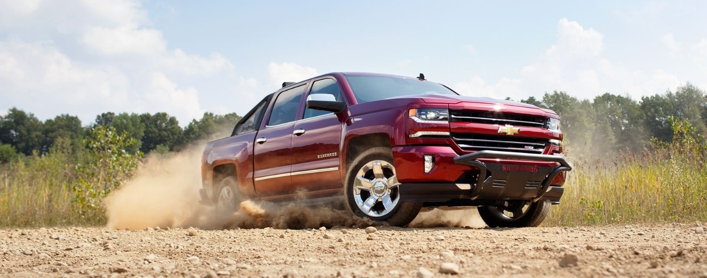 A maroon 2016 Chevy Silverado 1500 Z71 is shown driving to look at a used truck for sale near Bloomfield.