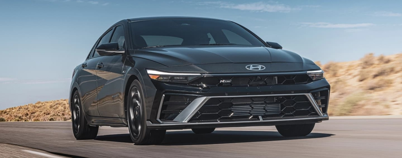 A dark grey 2024 Hyundai Elantra for sale in Houston driving on an open road.
