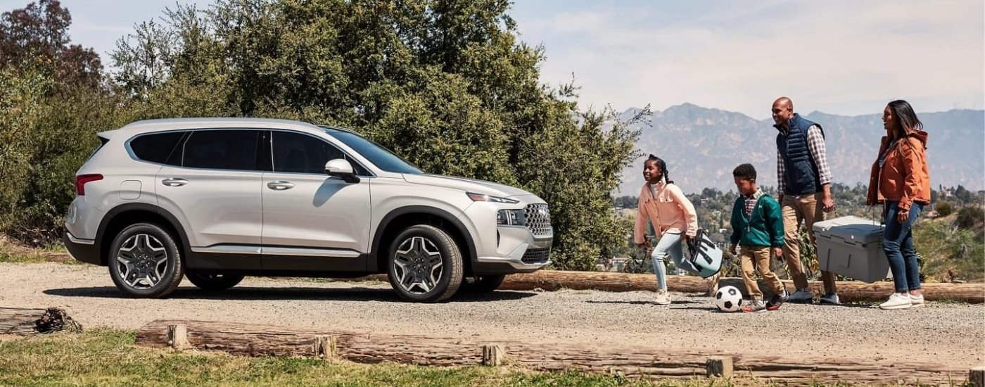 A family near a silver 2023 Hyundai Santa Fe PHEV.