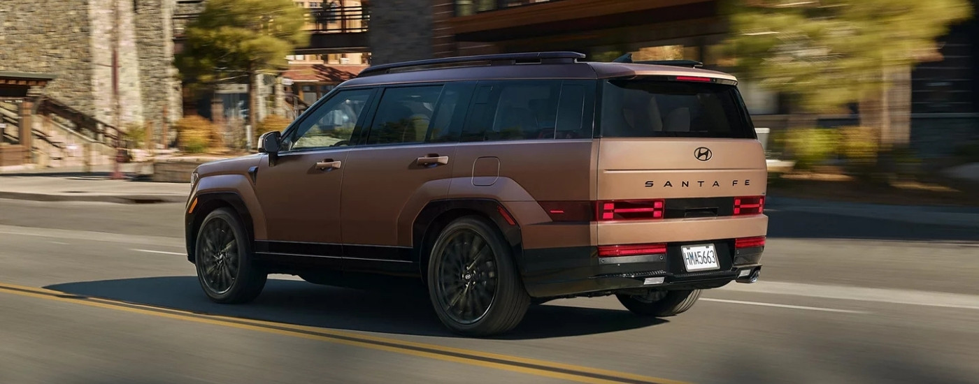 A brown 2025 Hyundai Santa Fe for sale in Houston driving on a city street.