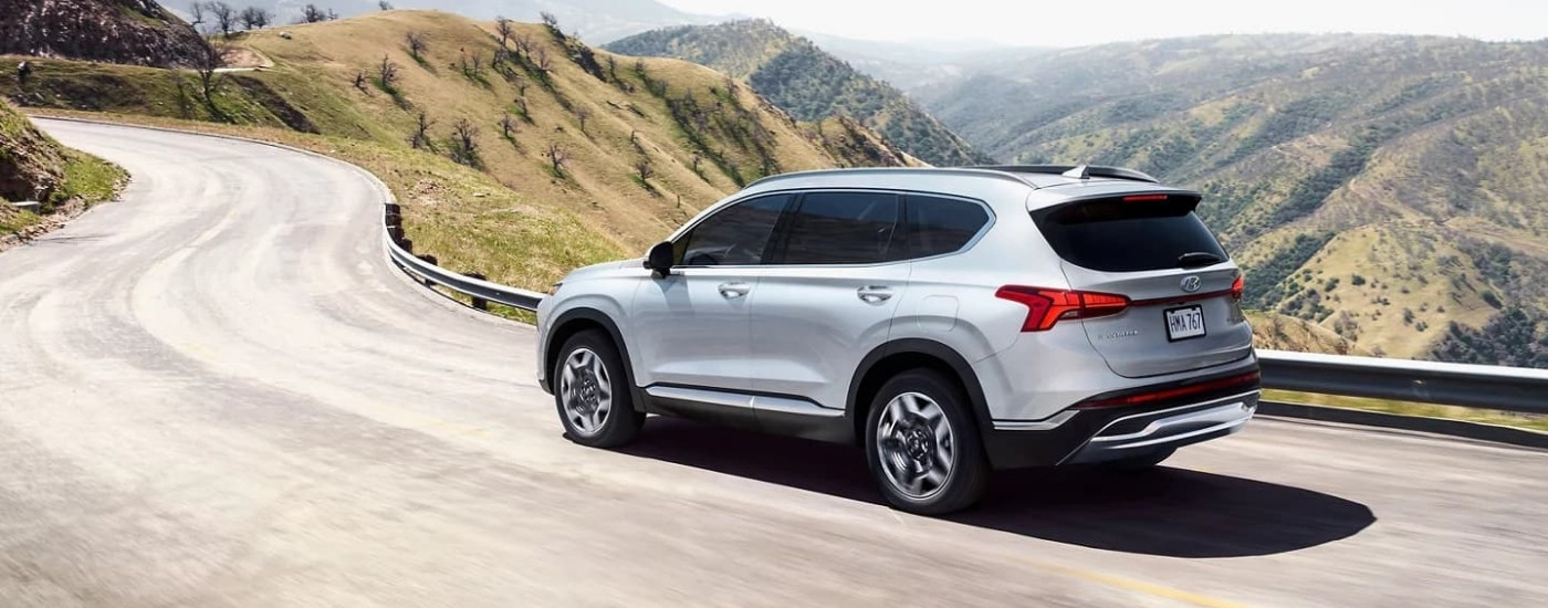 A silver 2023 Hyundai Santa Fe PHEV driving on a winding road.