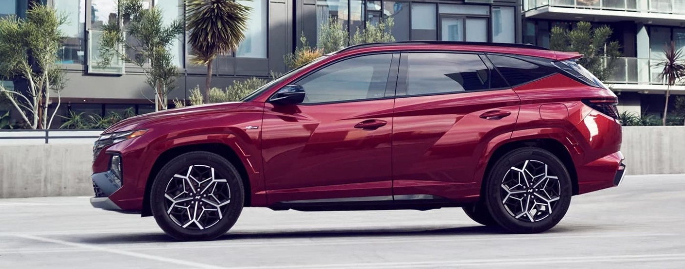 A red 2023 Hyundai Tucson N-Line from the side on a parking lot.
