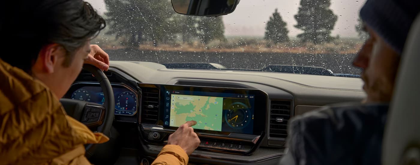 Two people using the map screen on the infotainment screen in a 2025 Chevy Silverado 1500