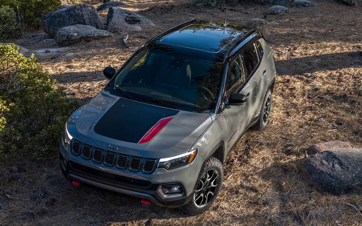 Green Jeep Compass parked on grassy terrain
