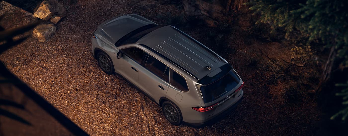 Grey 2025 Toyota Highlander parked outside of a cabin on gravel