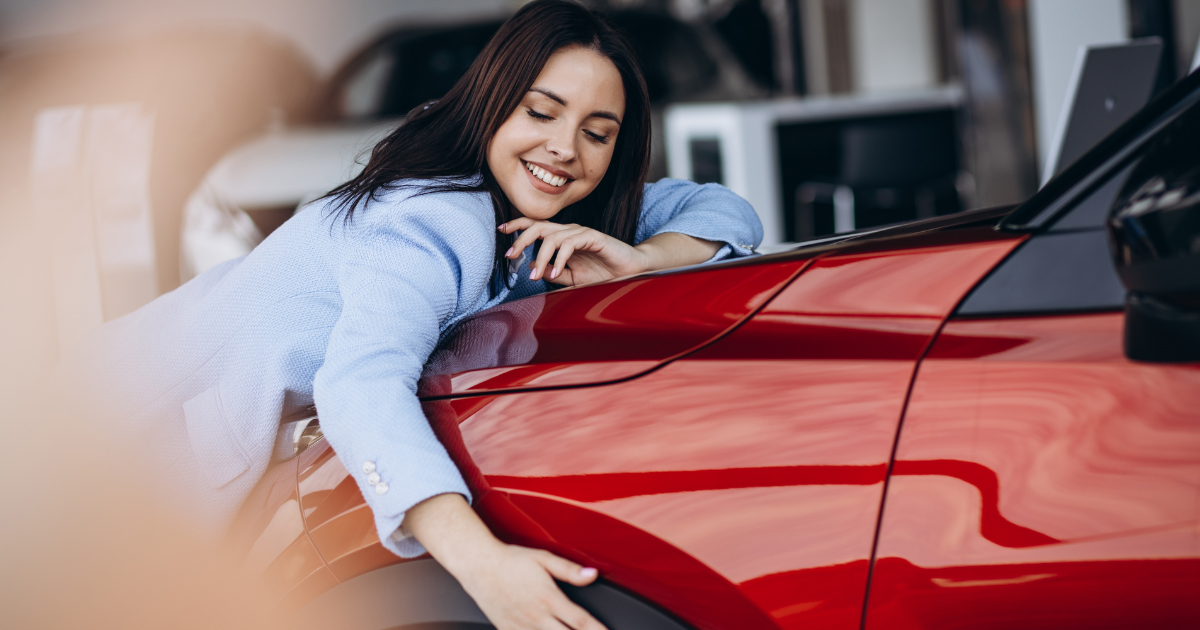 Smiling woman hugging the hood of her used Honda