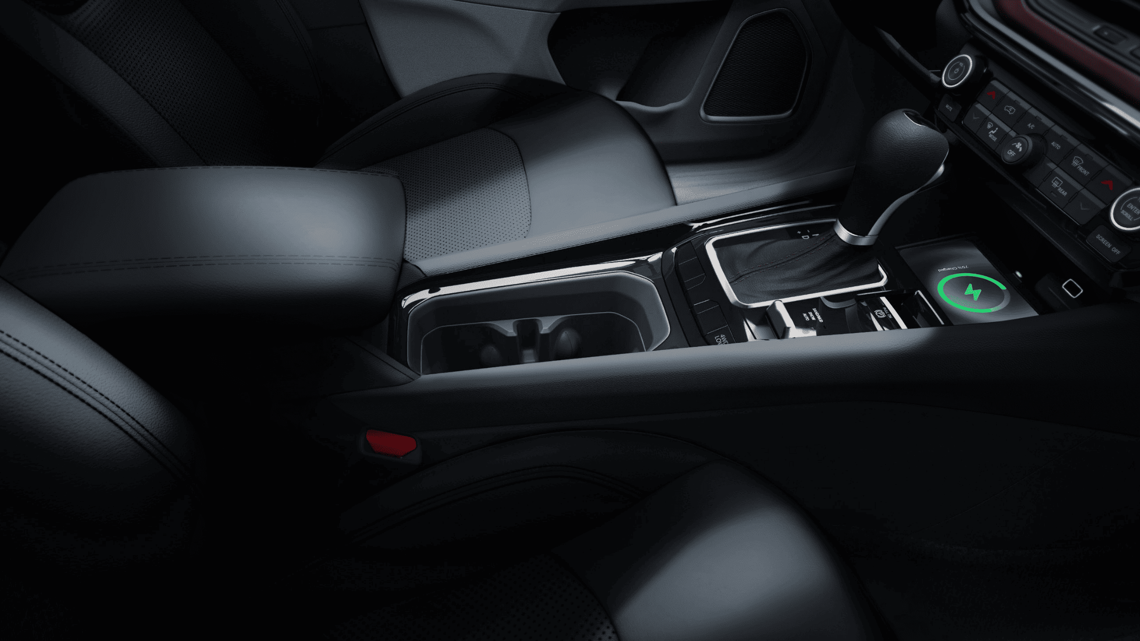 Center console of 2025 Jeep Compass featuring gear selector, wireless charging pad, and dual cupholders.