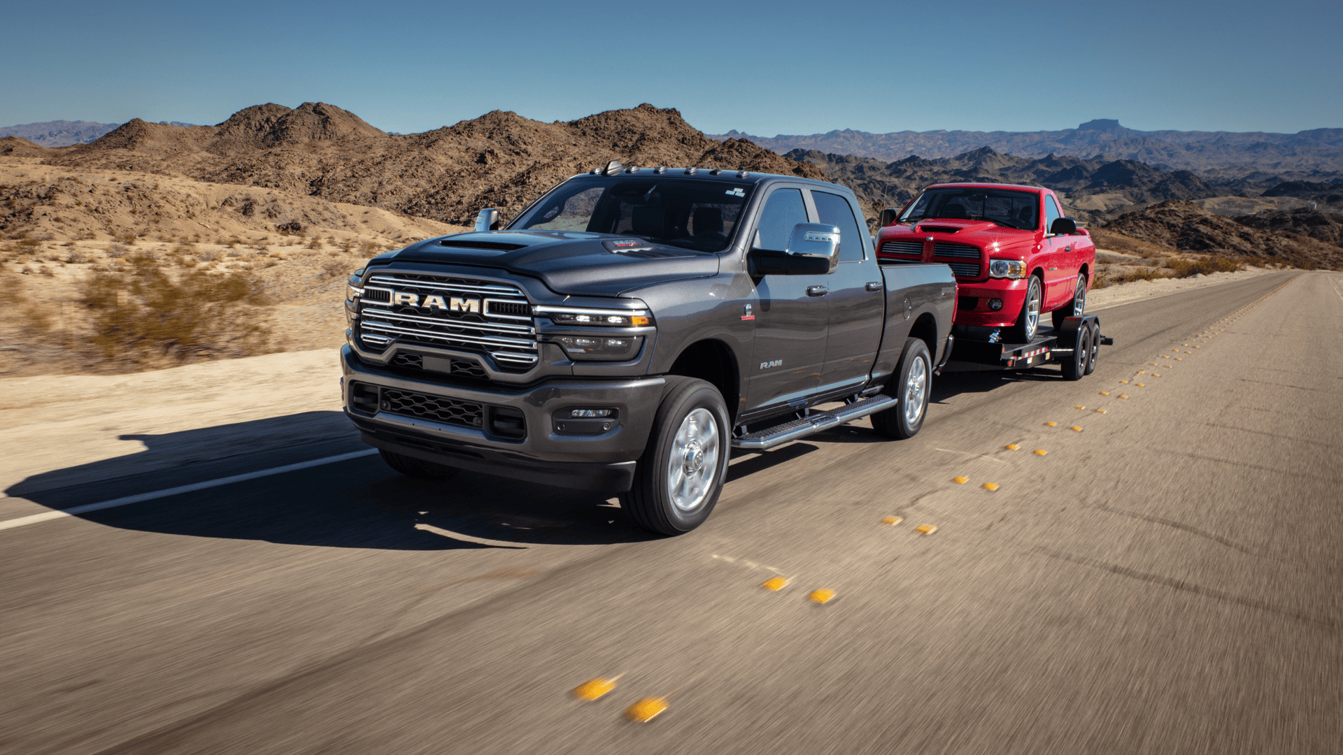 2025 Ram 2500 Laramie towing a red pickup on a highway in desert terrain, highlighting power and payload.