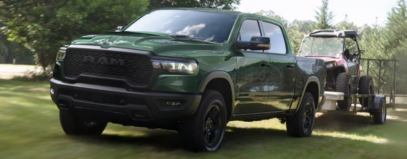 A green 2026 Ram 1500 Rebel towing an ATV.