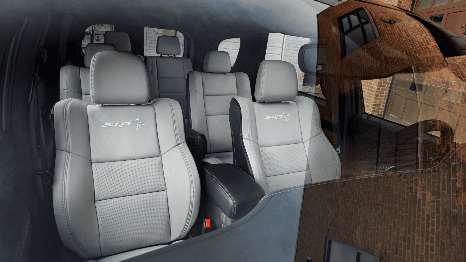 Close-up of the Dodge Durango SRT Hellcat's second-row leather seats with SRT and Hellcat logos embroidered in white, viewed through the windshield.