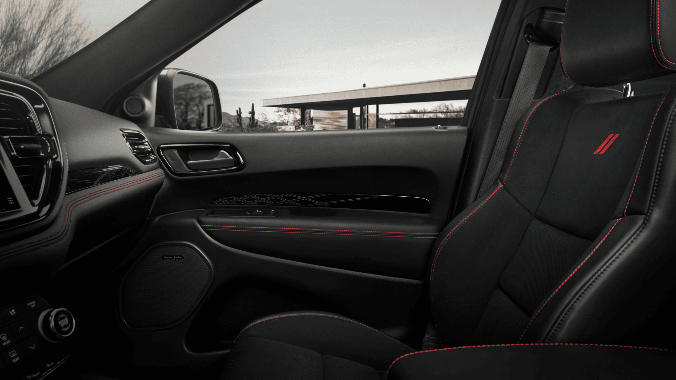 2026 Dodge Durango passenger seat view with black leather upholstery, red stitching, and Harman Kardon speaker.