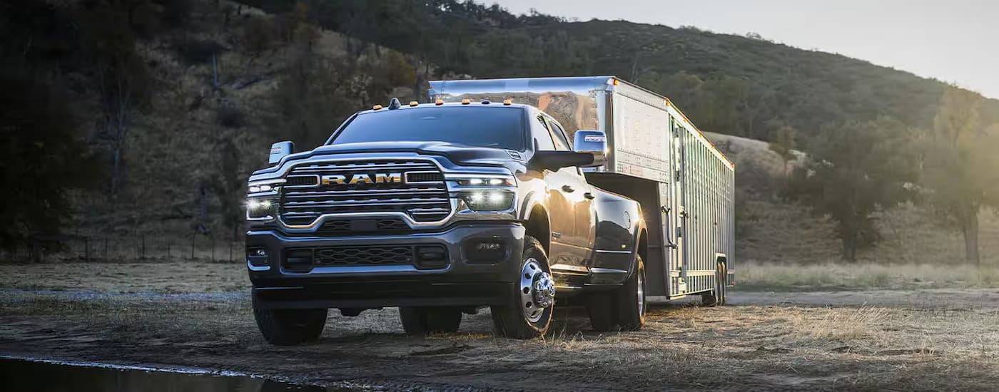 Silver 2025 Ram 3500 towing a large trailer over grass