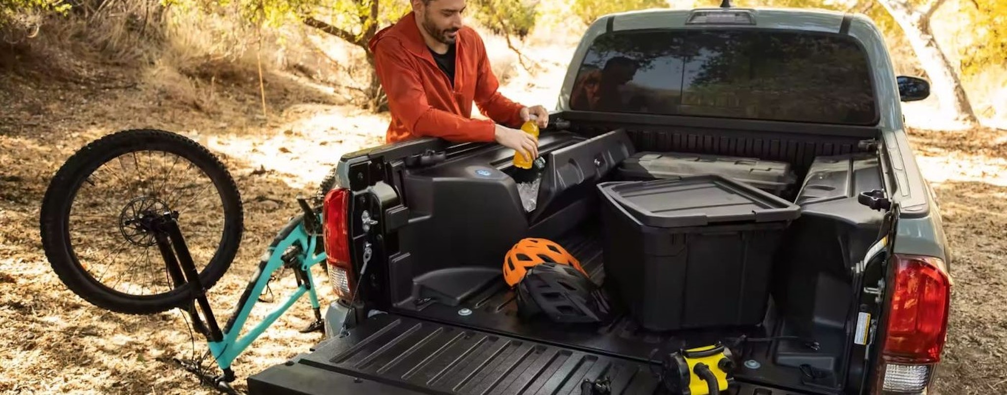 Man getting plastic tote out of the back of a grey 2023 Toyota Tacoma