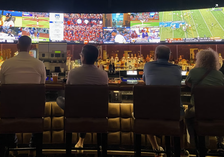 a group of people sitting at a sport bar watching tv