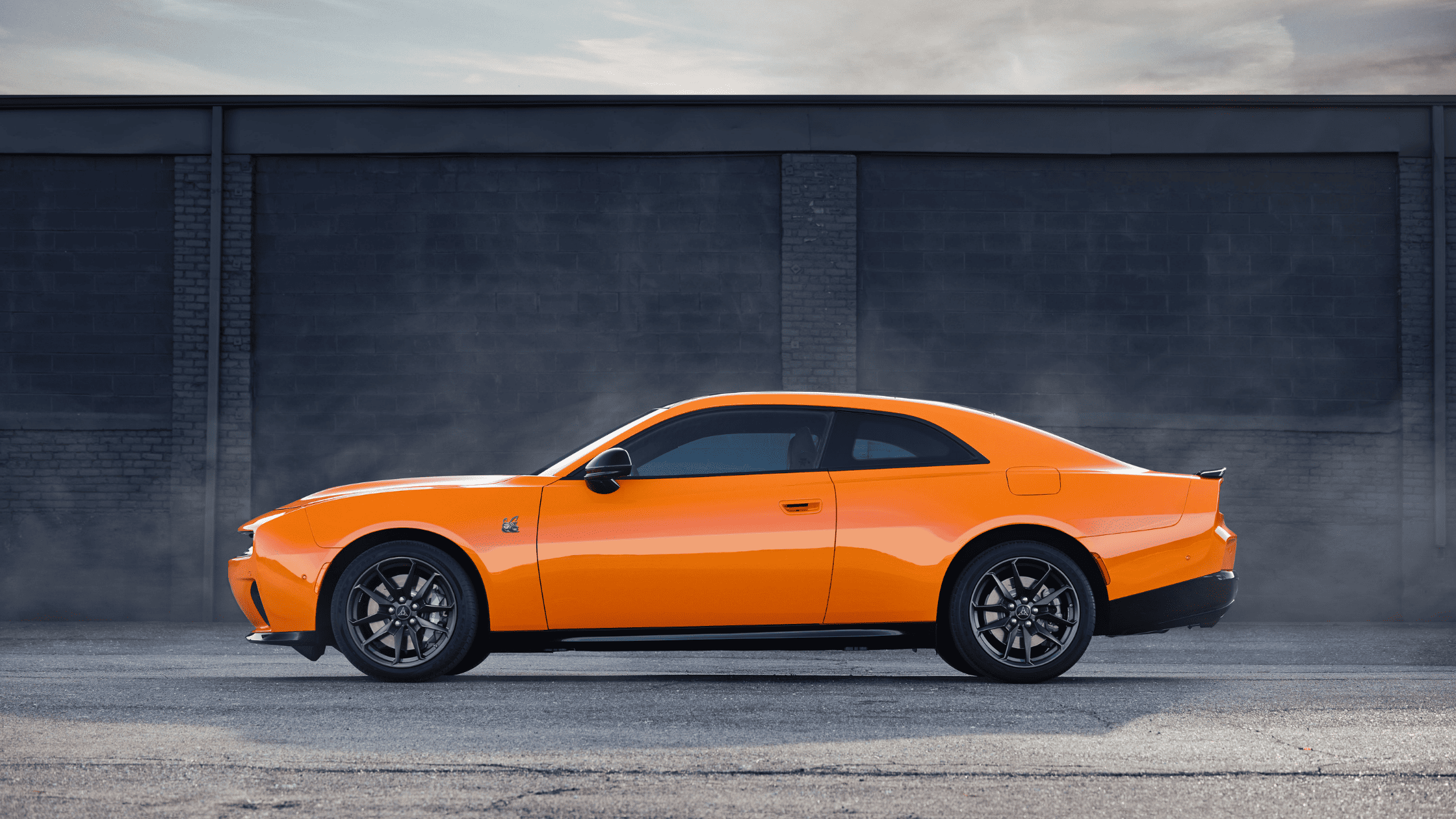 2026 Dodge Charger Daytona in bright orange side profile with sleek coupe styling.