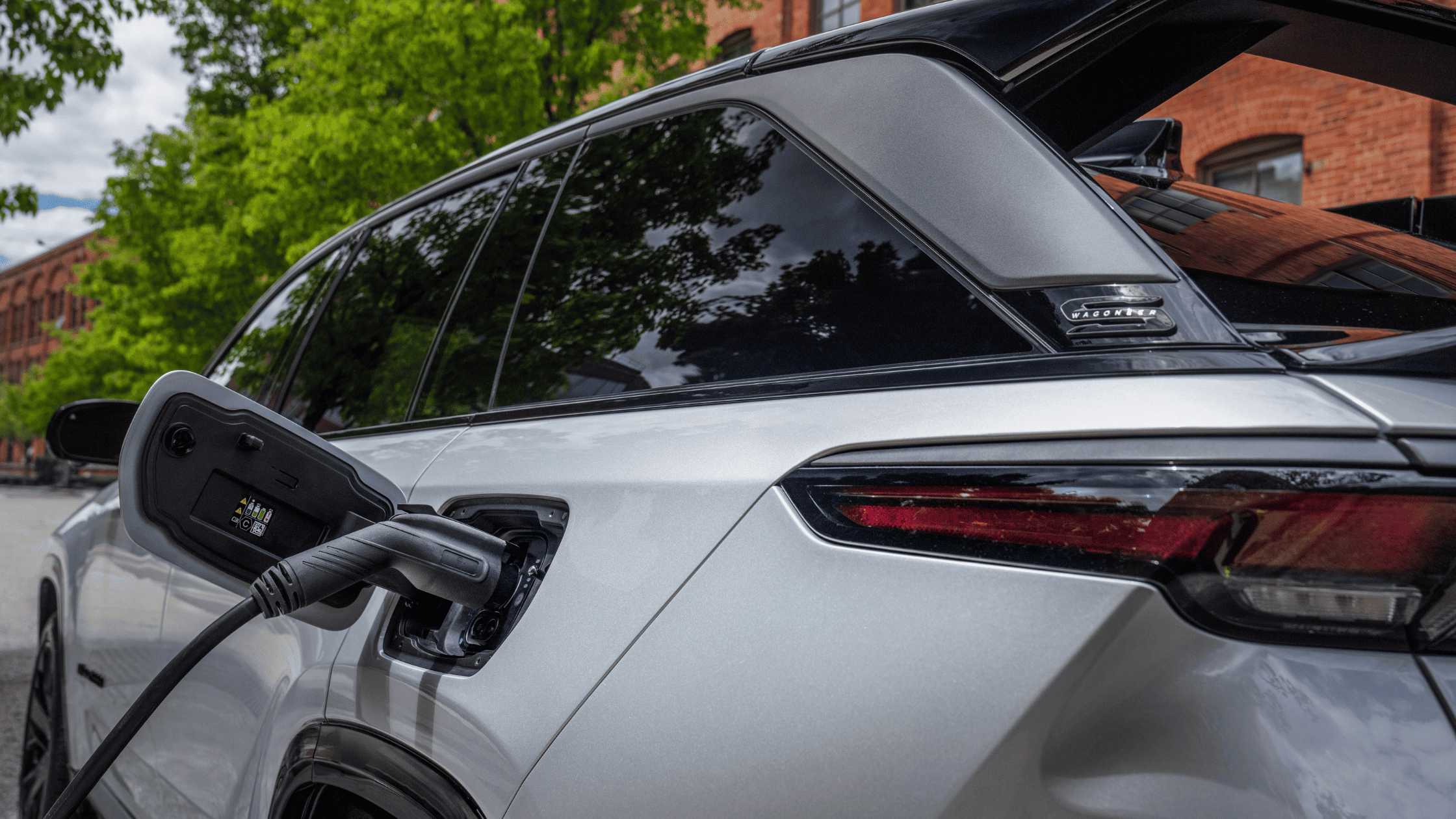 2025 Jeep Wagoneer S charging port close-up with cable connected to rear side.