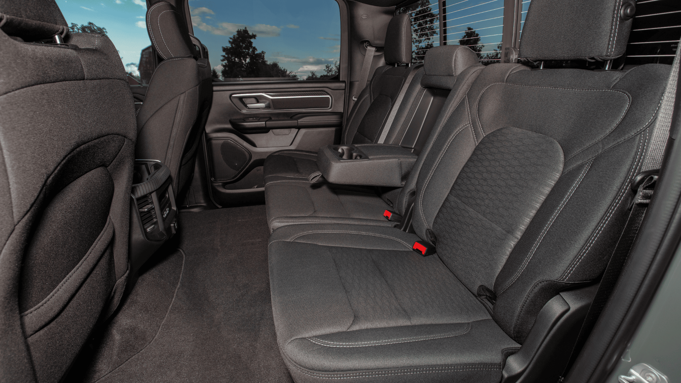 2026 Ram 1500 rear cabin with spacious black cloth seats and foldable armrest view.