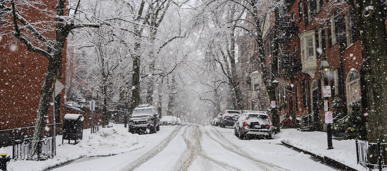 A snowy street with cars parked on the side of it