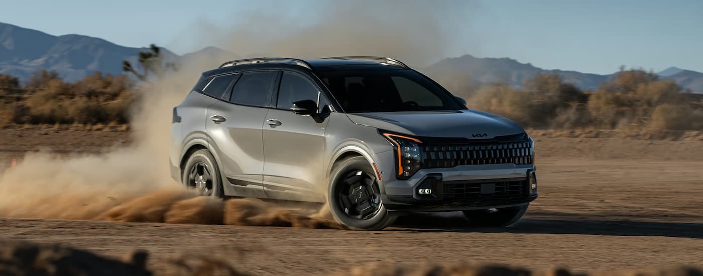 Grey 2026 Kia Sportage off-roading on a sandy lot