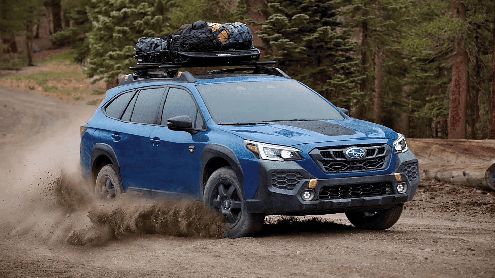 2025 Subaru Outback with cargo gear on roof rack, kicking up dirt on a rugged mountain road near Beckley WV.