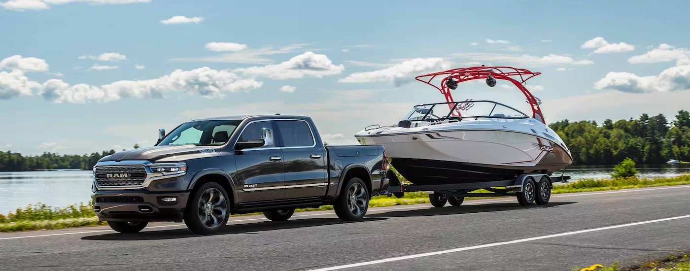 A grey 2025 Ram 1500 from the side while towing a boat.