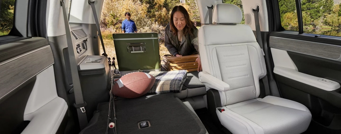 Woman putting cargo in the back of a 2025 Hyundai Santa Fe with folded seats