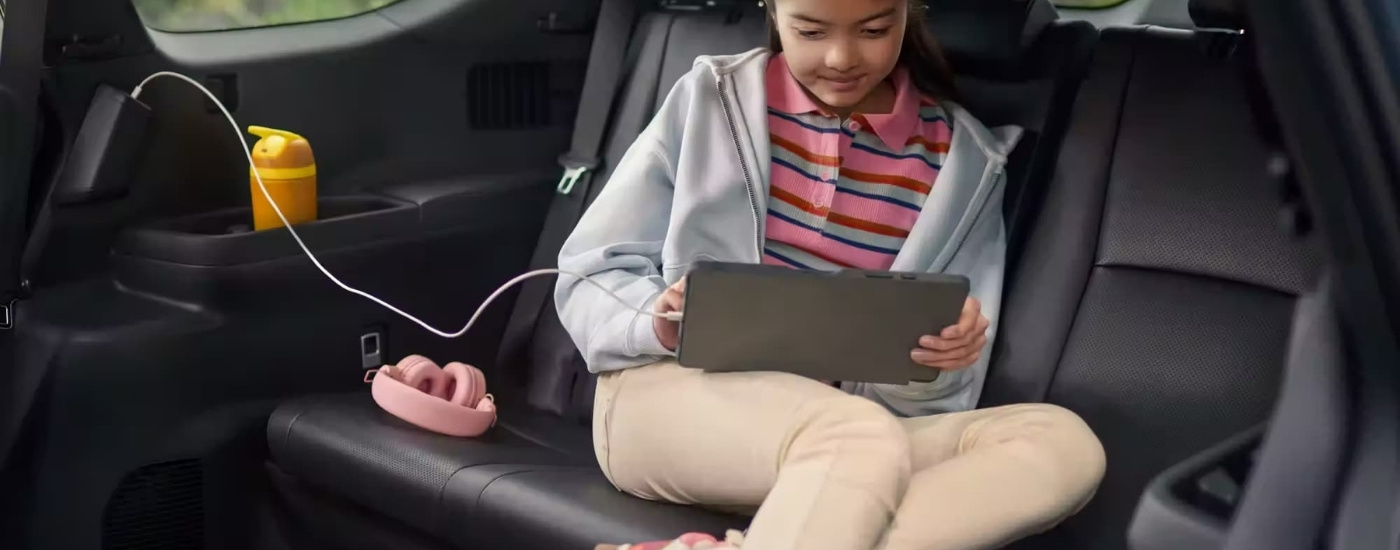 Kid using a tablet in a 2024 Toyota Grand Highlander for sale in San Marcos