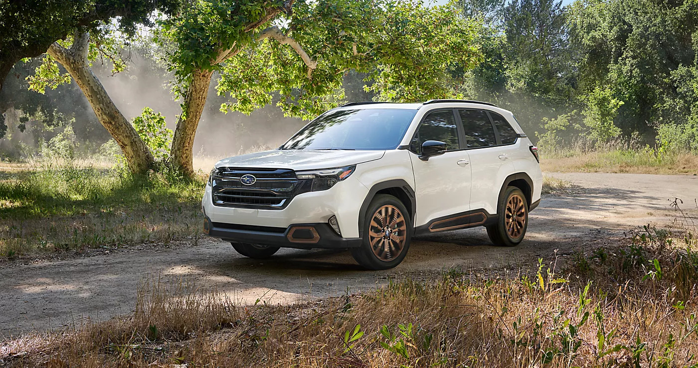 a white 2025 subaru forester driving on a gravel road