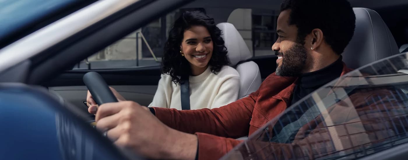 Couple in the front seats of a blue 2026 Hyundai Tuscon
