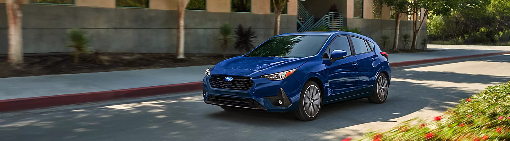 2025 subaru impreza in blue driving past an apartment building