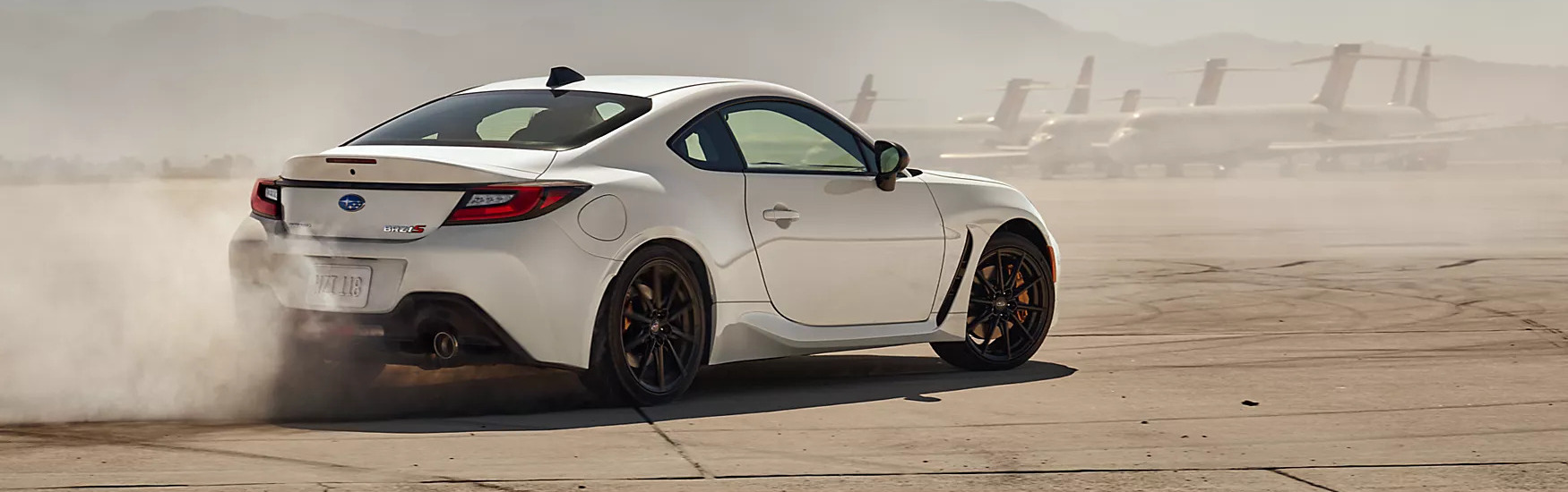  a white 2025 subaru brz racing down a road at an airport