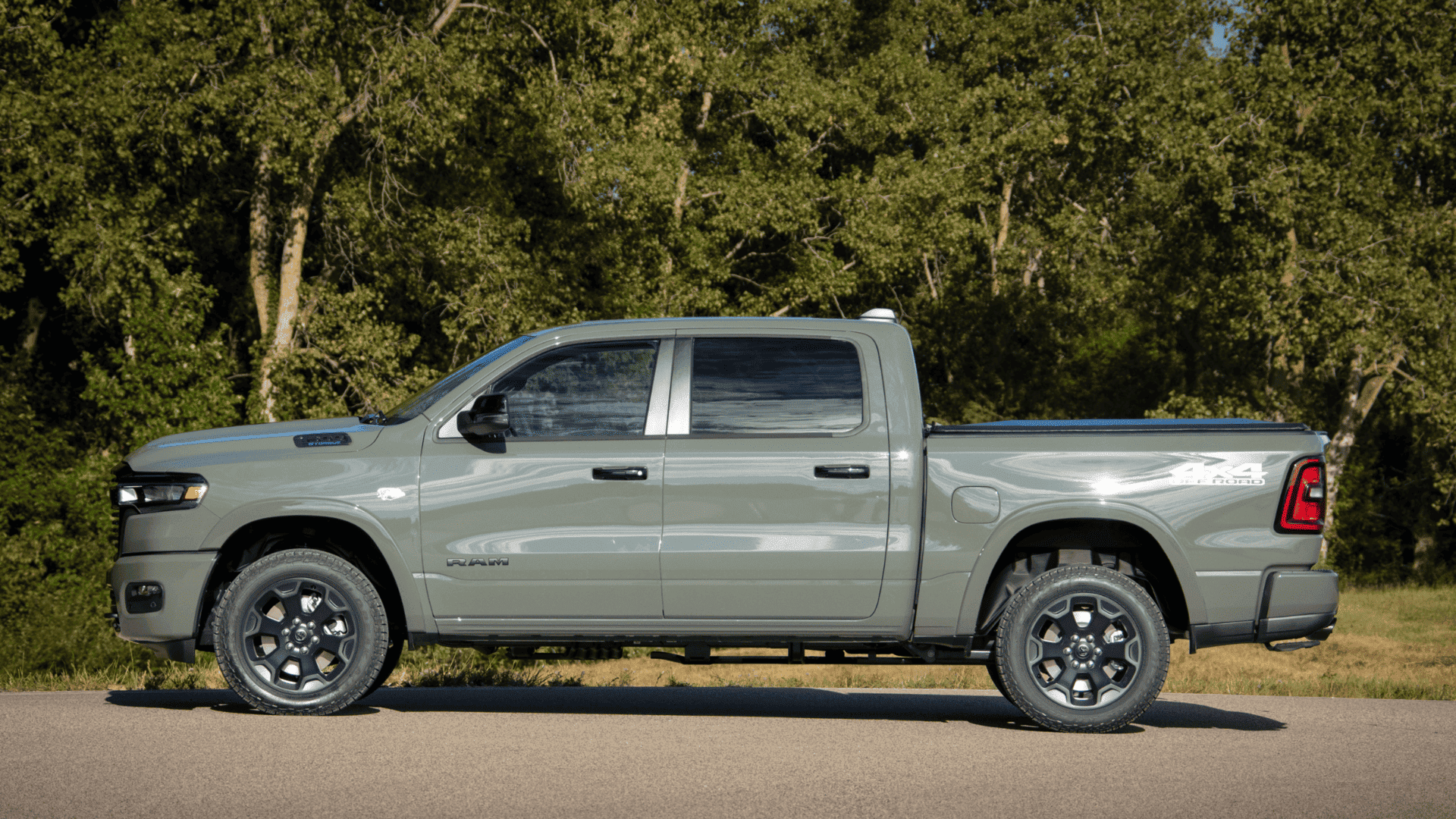 2026 Ram 1500 Hemi pickup in green side profile view parked on pavement with forest backdrop.